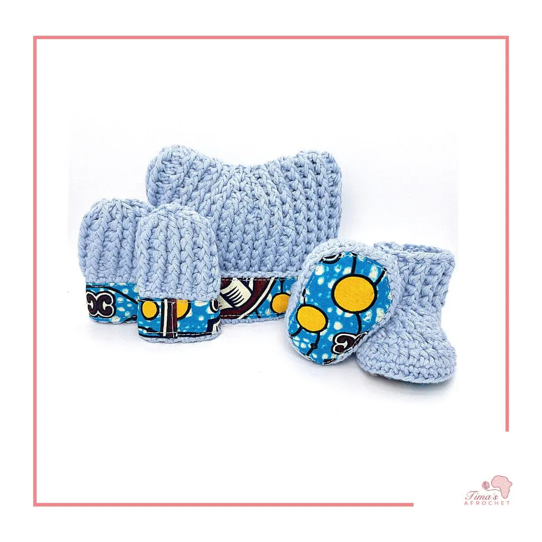 Image is a light blue crochet bundle set which includes hat, booties, mittens. Each item has African fabric on the soles and rims.  Perfect for keeping baby stylish, comfortable and representing culture.