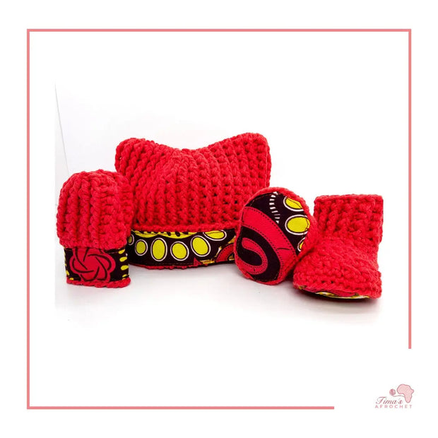 Image is a red crochet bundle set which includes hat, booties, mittens. Each item has African fabric on the soles and rims.  Perfect for keeping baby stylish, comfortable and representing culture.