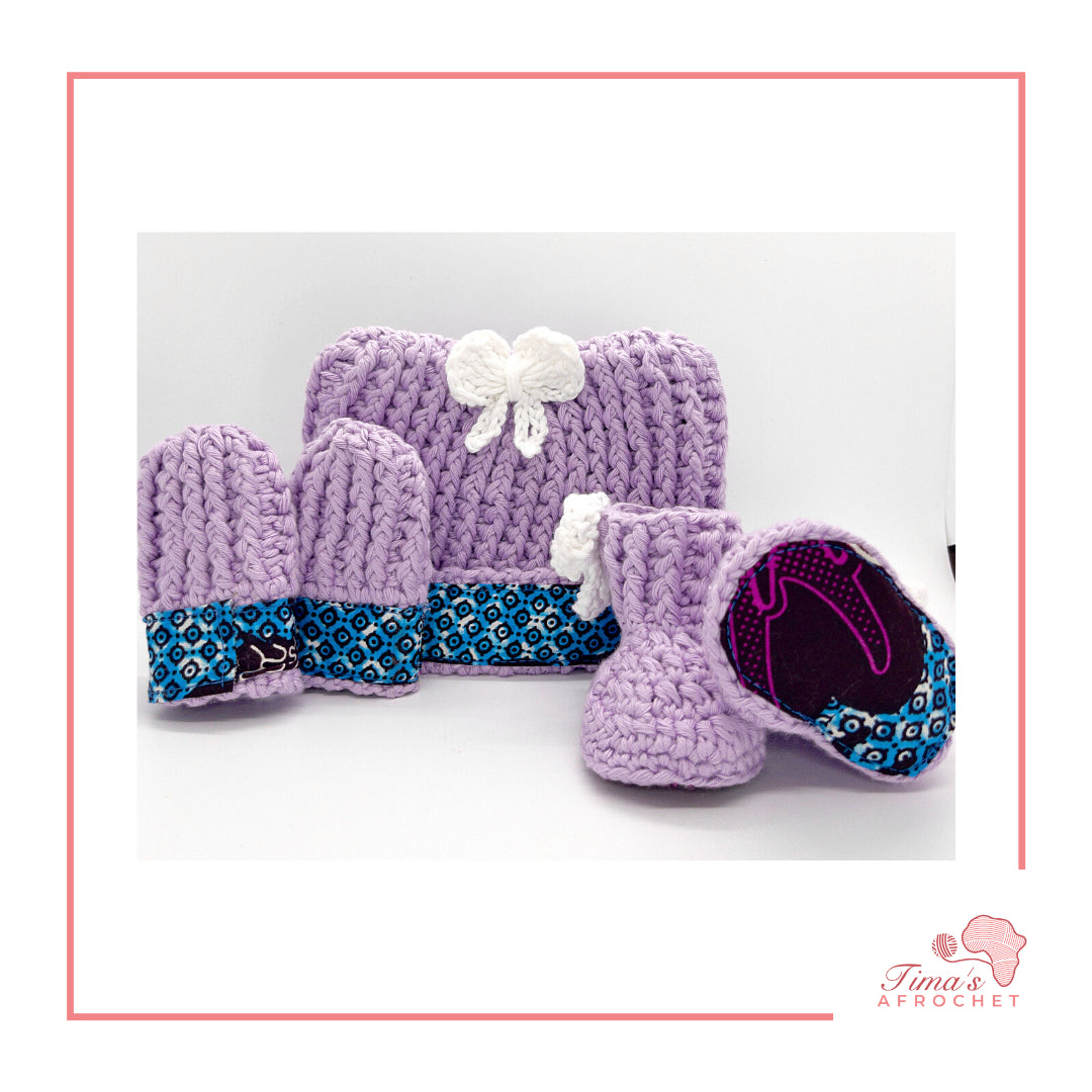 Image is a light purple crochet bundle set which includes hat, booties, mittens. Each item has African fabric on the soles and rims.  Perfect for keeping baby stylish, comfortable and representing culture.