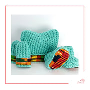 Image is a light aqua crochet bundle set which includes hat, booties, mittens. Each item has African fabric on the soles and rims.  Perfect for keeping baby stylish, comfortable and representing culture.
