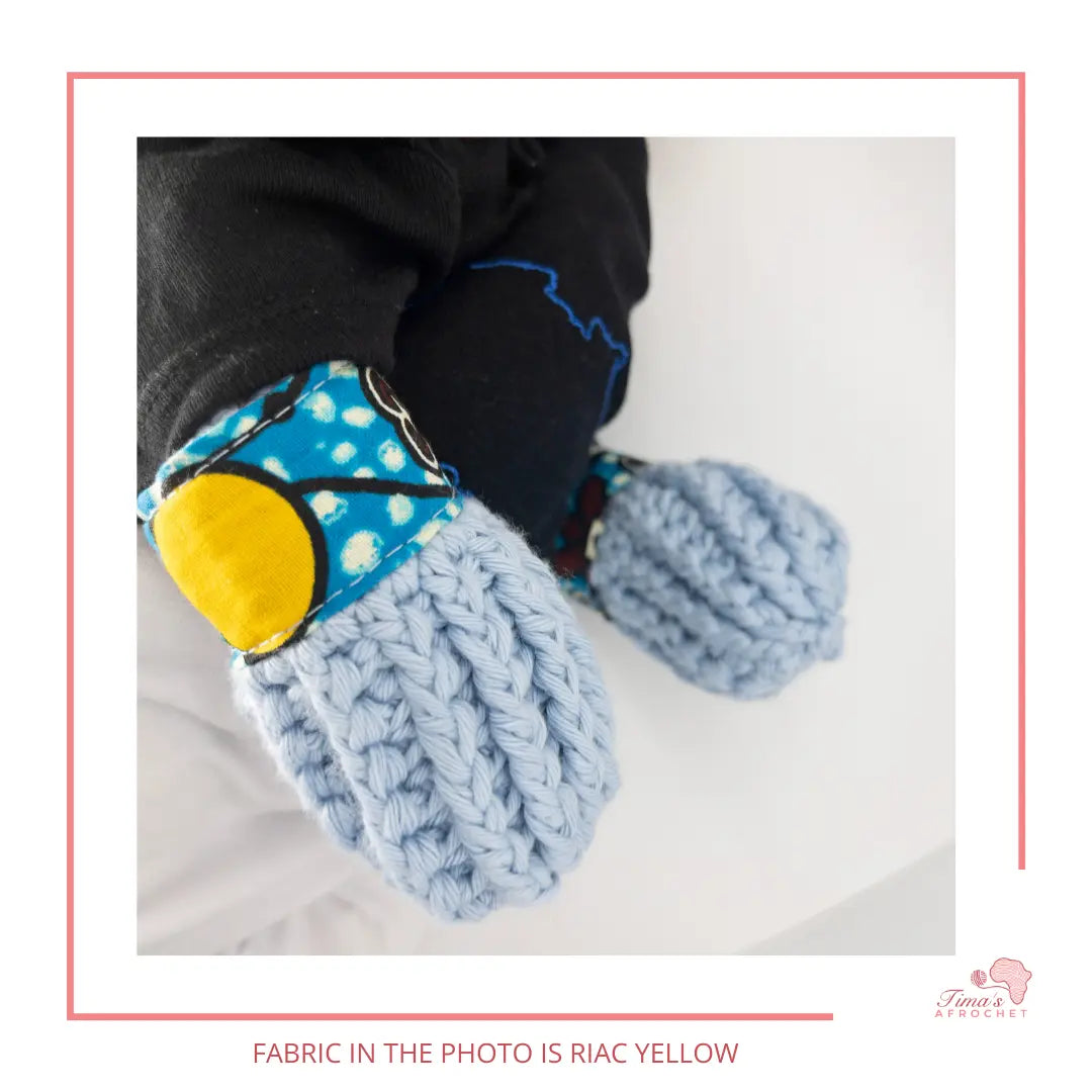 Image is a pair of crochet light blue baby mittens with authentic African Ankara fabric on the rim where the wrists is.Perfect for keeping baby stylish, comfortable and representing culture. 
